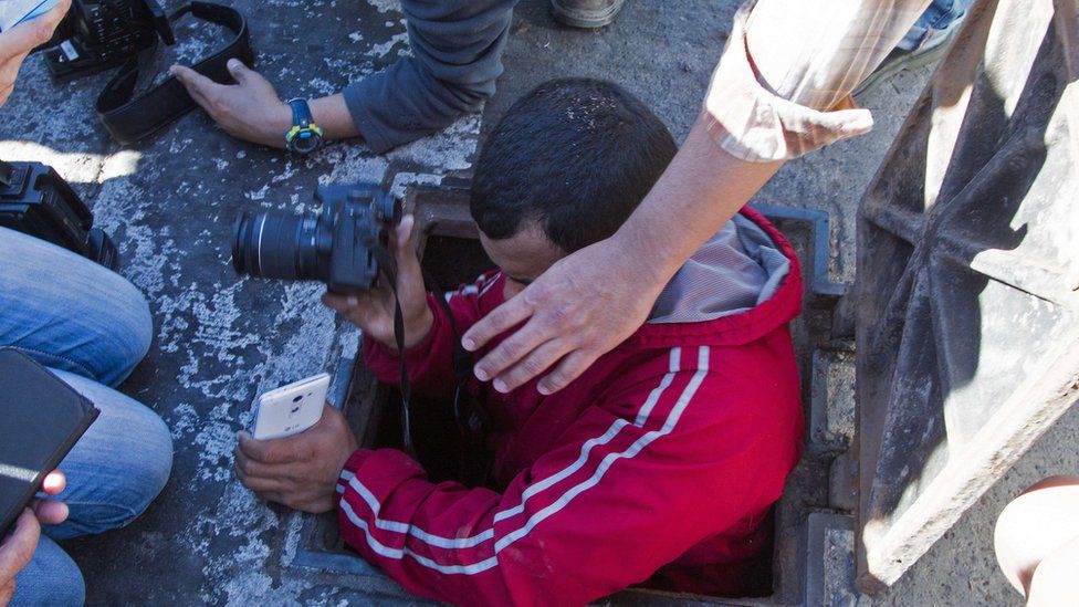A journalist enters a manhole of the sewer system through which drug kingpin Joaquin "El Chapo" Guzman tried to escape