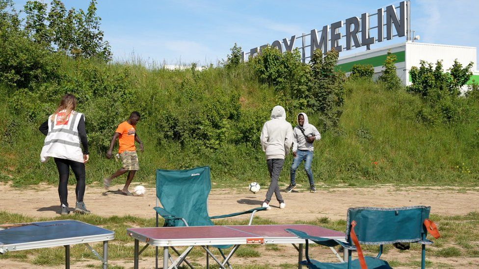 Migrants play football in a camp near Calais