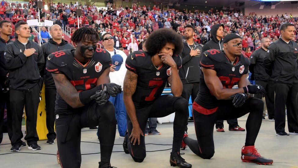 Eli Harold, Colin Kaepernick and Eric Reid (35) kneel in protest during the playing of the national anthem before a NFL game