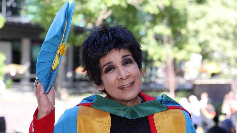 Moira Stuart in academic robes holds her cap off her head