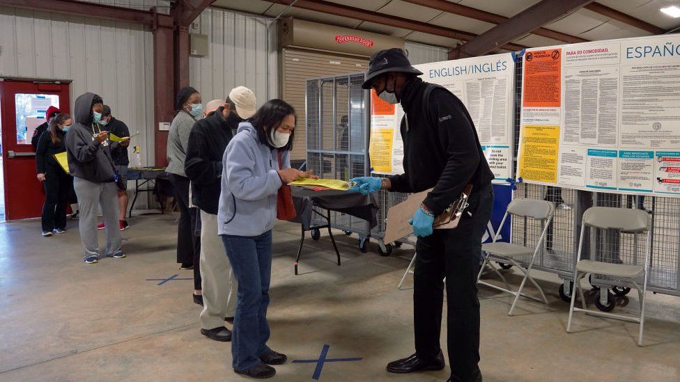 A poll worker helps voters fill out forms as they stand in line to cast their ballots for a Senate election in Atlanta, Georgia, on 14 December 2020