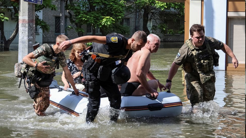 Police evacuate local residents from a flooded area after the Nova Kakhovka dam breached, amid Russia's attack on Ukraine, in Kherson, on 7 June 2023