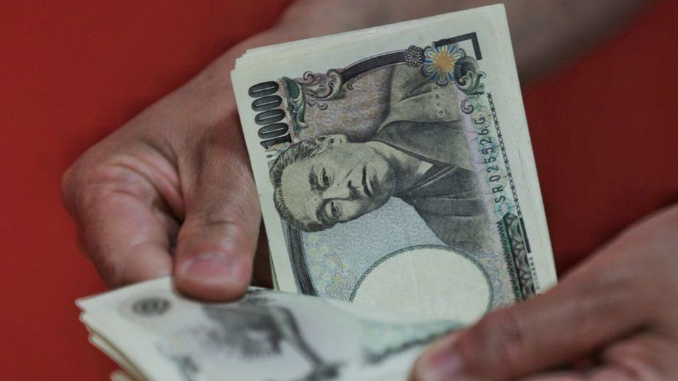 Человек, считающий банкноты в японских иенах.