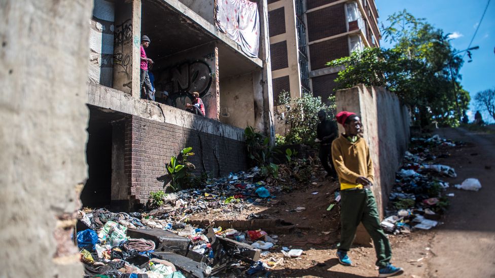 Неопознанный мужчина выходит из заброшенного здания Сан-Хосе в Йоханнесбурге, Южная Африка