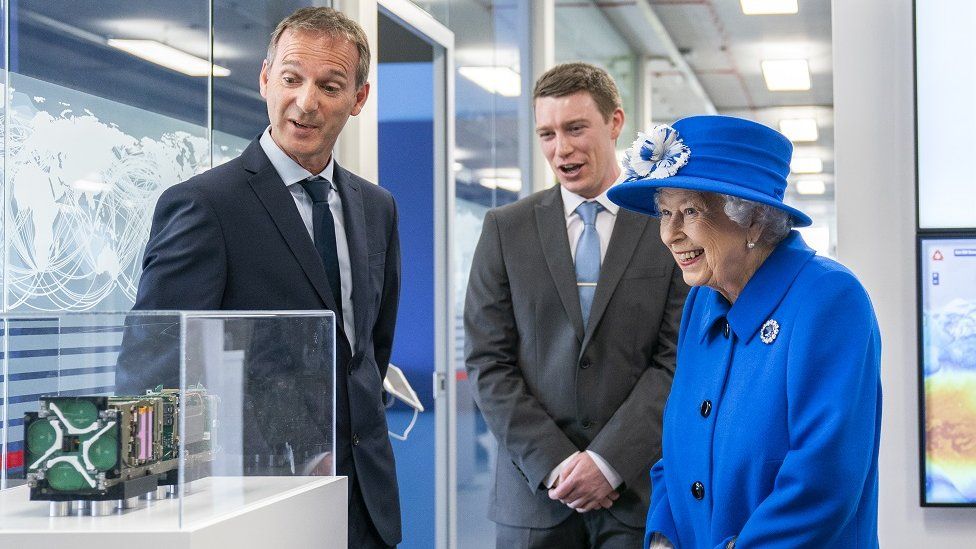 The Queen looks at a model with two men