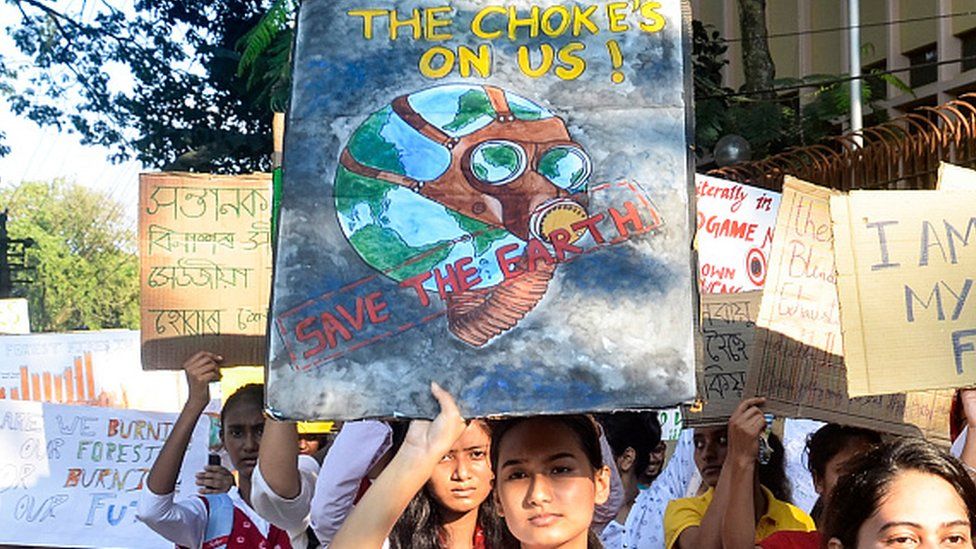 Студенты и люди держат плакаты, участвуя в акции протеста против изменения климата