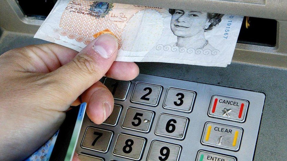Close up of hand removing £10 from ATM