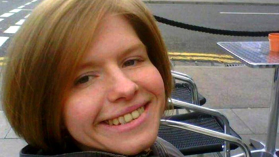 Shauna Gauntlett posing for a photo, seated next to a table outside on a pavement