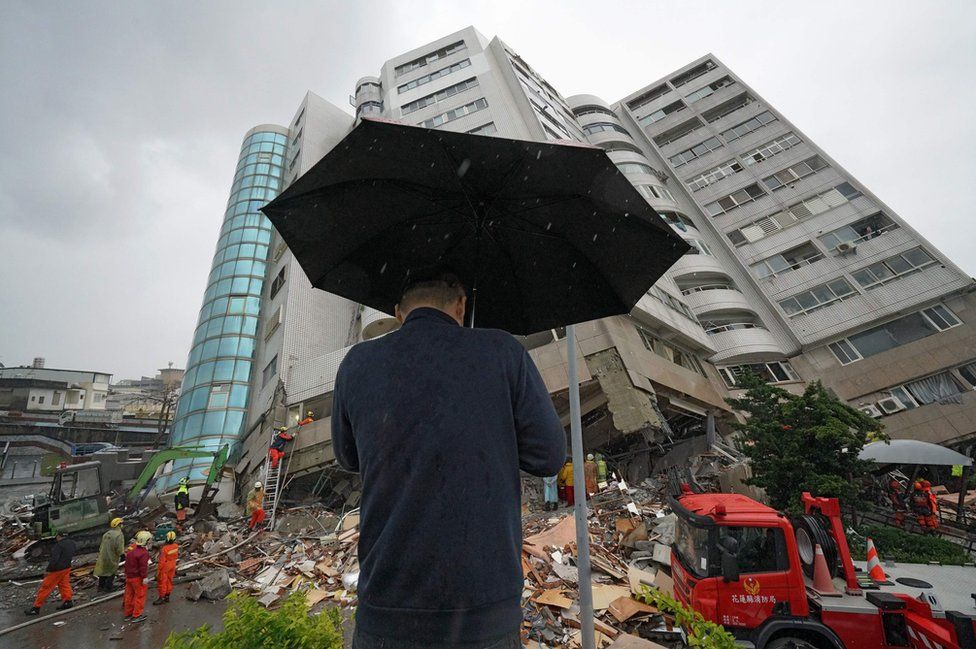 A man prays outside a building which tilted to one side after its foundation collapsed in Hualien