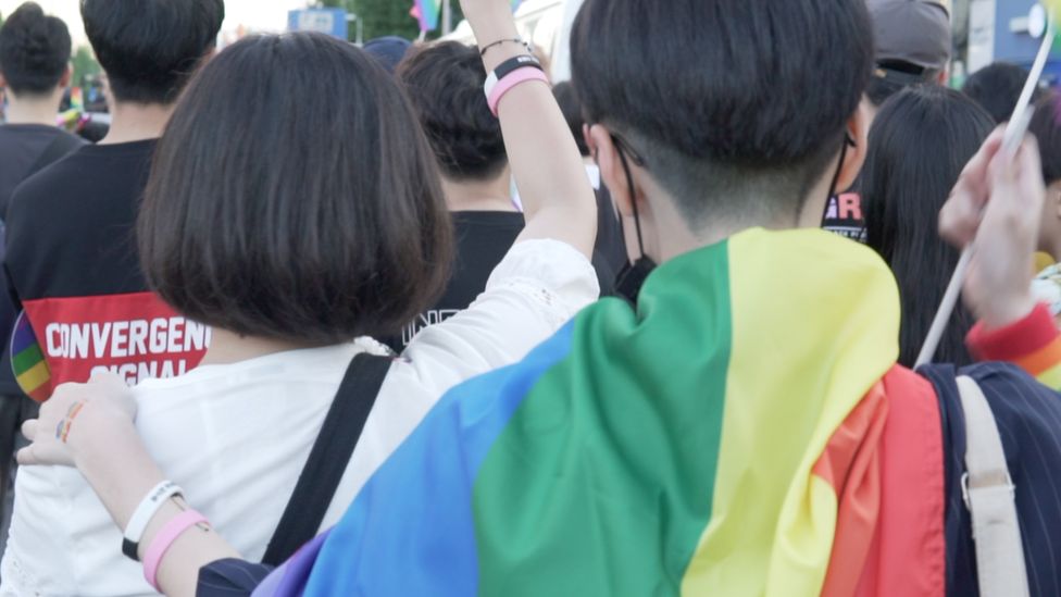 Attendees at Incheon Queer Festival draped in a rainbow flag