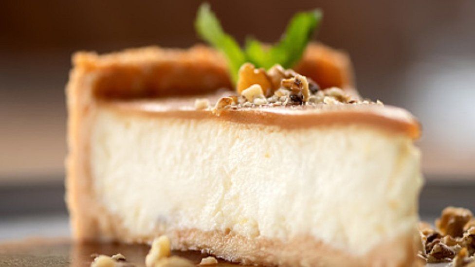 Cheesecake with caramel, sprinkled with nuts and decorated with mint on a plate