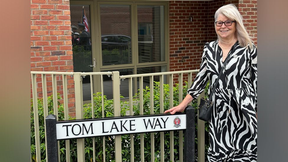 Carol Lake and the sign Tom Lake Way