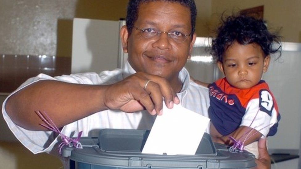 Wavel Ramkalawan casts his vote as he holds his nine-month-old son Amos at a polling station in St. Louise constituency, Seychelles, July 30, 2006