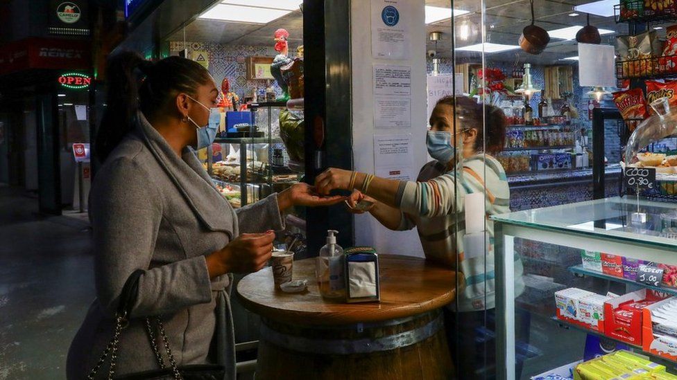 A woman buys a coffee at the entrance of a partially opened cafe as required under Portugal's government plan to gradually lift a lockdown imposed in mid-January to tackle what was then the world's worst coronavirus disease (COVID-19) surge, in Porto, Portugal March 15, 2021.