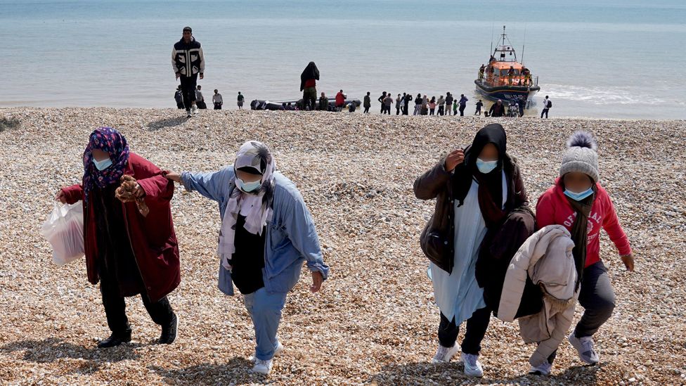 People thought to be migrants make their way up the beach after arriving on a small boat at Dungeness in Kent. Monday July 19, 2021.. They were later taken way by Border Force staff.