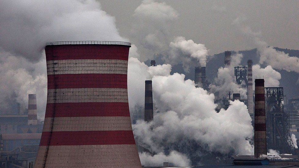 Smoke billows from smokestacks and a coal fired generator at a steel factory