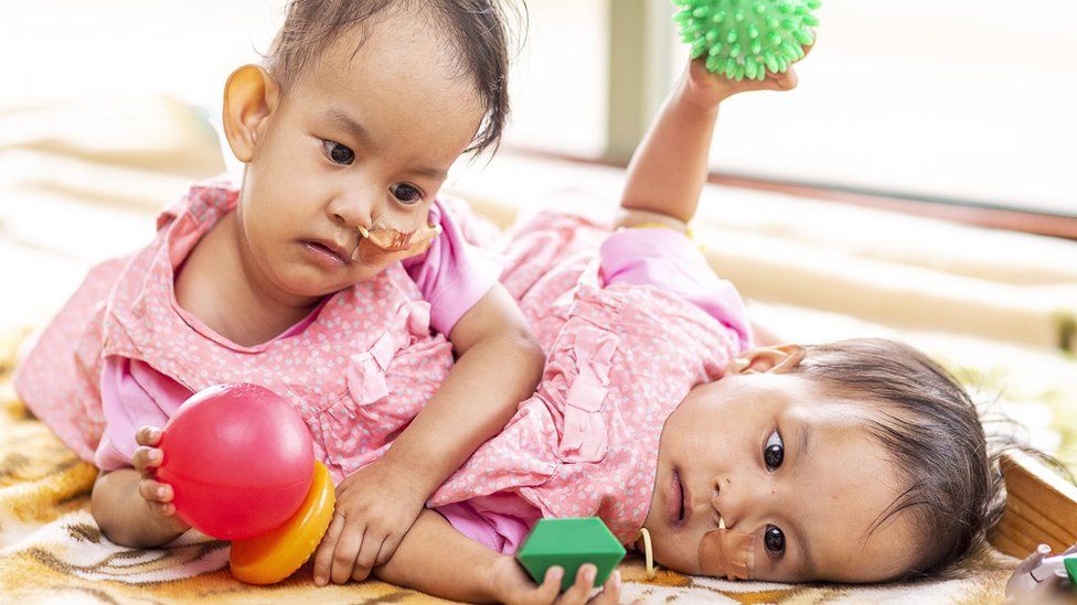 Bhutanese twins Nima and Dawa Pelden play with toys