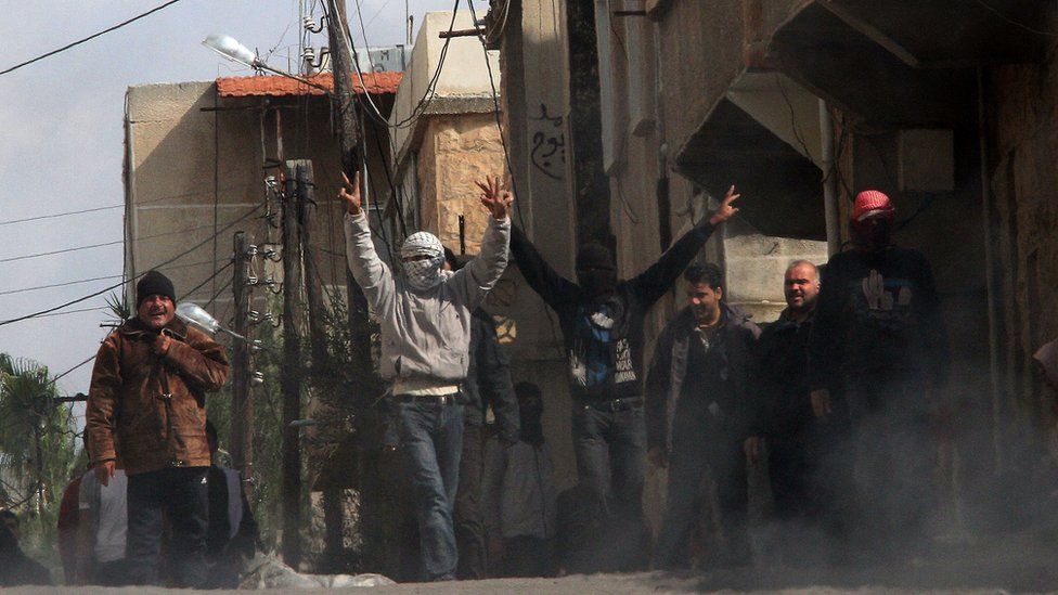 Anti-government protesters gesture as they gather on the streets of Deraa on 23 March 2011