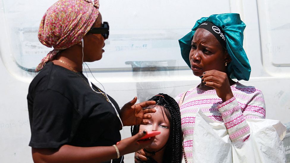 Two women negotiate the price of a wig at Wuse Market, Abuja, Nigeria - Wednesday 26 January 2022