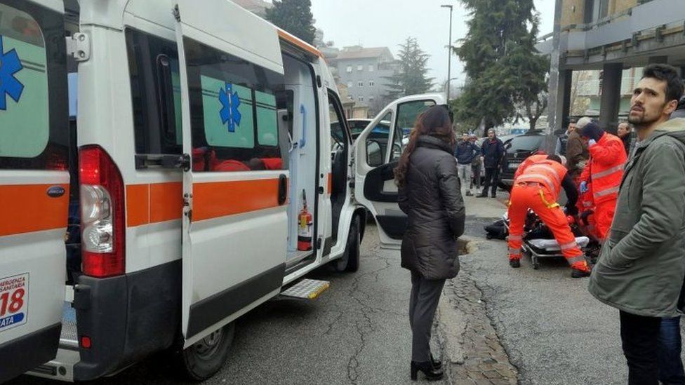 Paramedics treat an injured person that was shot from a passing vehicle in Macerata, Italy, 3 February 2018