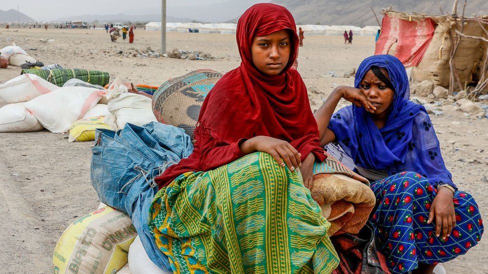 Two Woman sit on bags of aid dispensed at the Silsa Internally Displaced Peoples' (IDP) camp on March 24, 2022 in Silsa, Ethiopia.