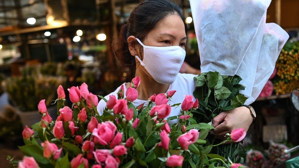 A woman wearing a mask carrying flowers in Hanoi