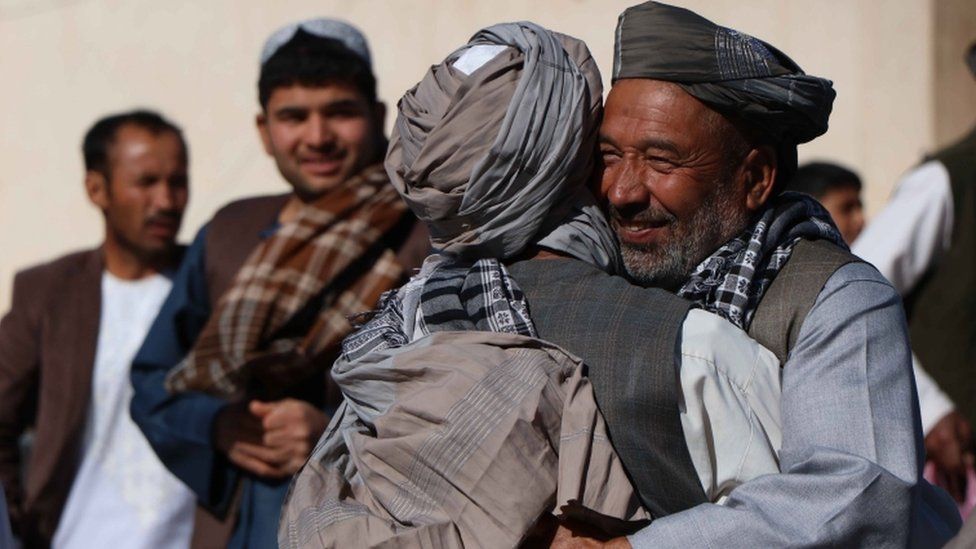 Afghans greet each other after offering special prayers on on Eid al-Fitr in Herat, Afghanistan, 15 June 2018.