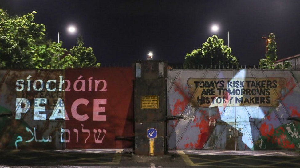 The word 'peace' in Irish, English, Arabic and Hebrew projected at the Lanark Way peace gates in Belfast