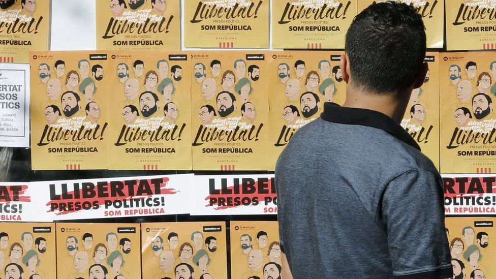 A man looks at posters during a demonstration to protest against the imprisonment of eight former members of Catalan government