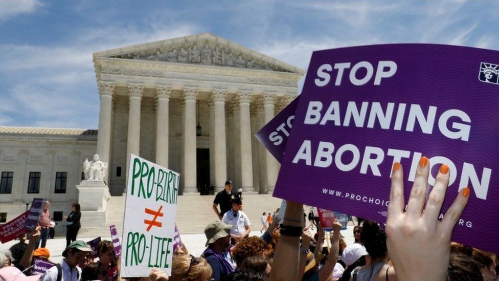A protester outside the Supreme Court in Washington DC holds a sign reading, "Stop banning abortion"