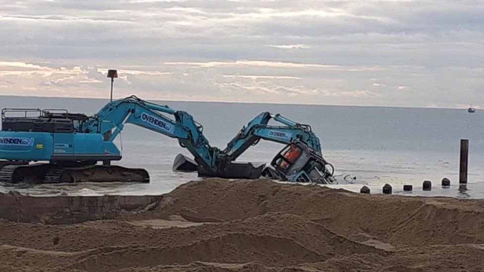 A digger on its side in the sea