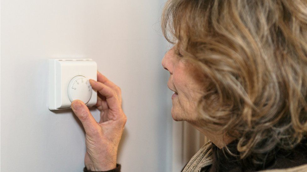 Woman turning down thermostat