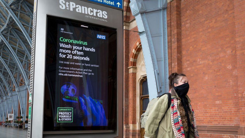 A woman leaving St Pancras International station wearing a mask