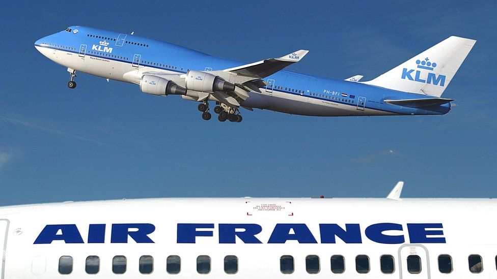 The top of one airplane, emblazoned with AIR FRANCE, occupies the lower third of this photo, while a blue KLM plane soars above it