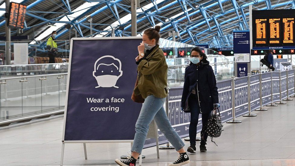 A sign tells passengers to "wear a face covering" at Waterloo train station in central London