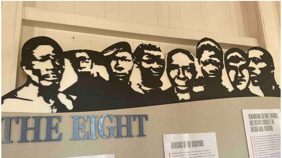 A museum display shows the imagined faces of eight men in silhouette with the words 'the eight'