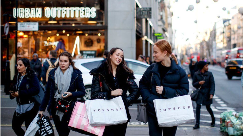 Young adult shoppers on Oxford Street carrying shopping bags