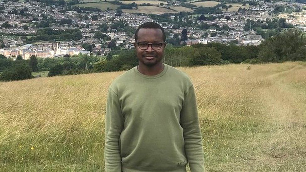 Ukrainian Excel wearing a green jumper with Gloucestershire countryside behind him and blue skies