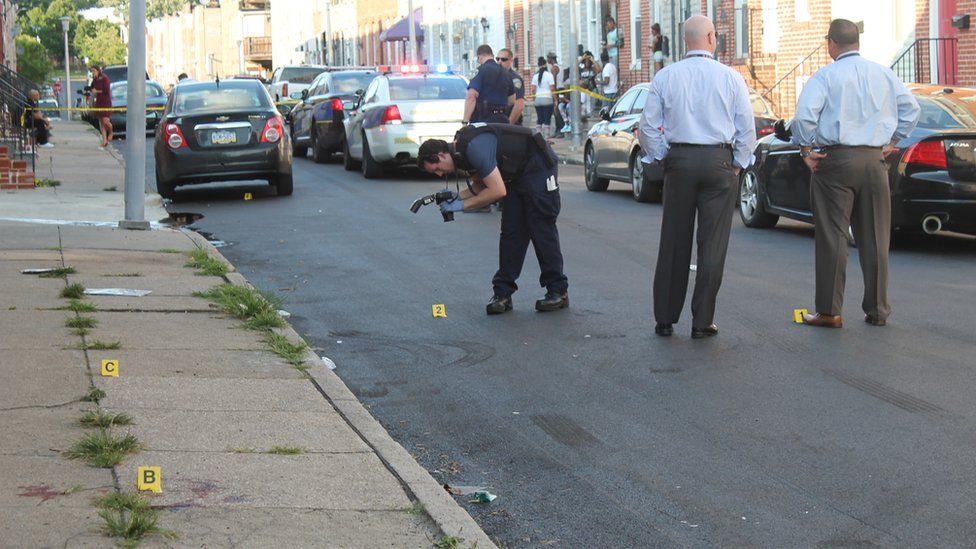 Baltimore police detectives on the scene of a homicide in the Pigtown neighbourhood