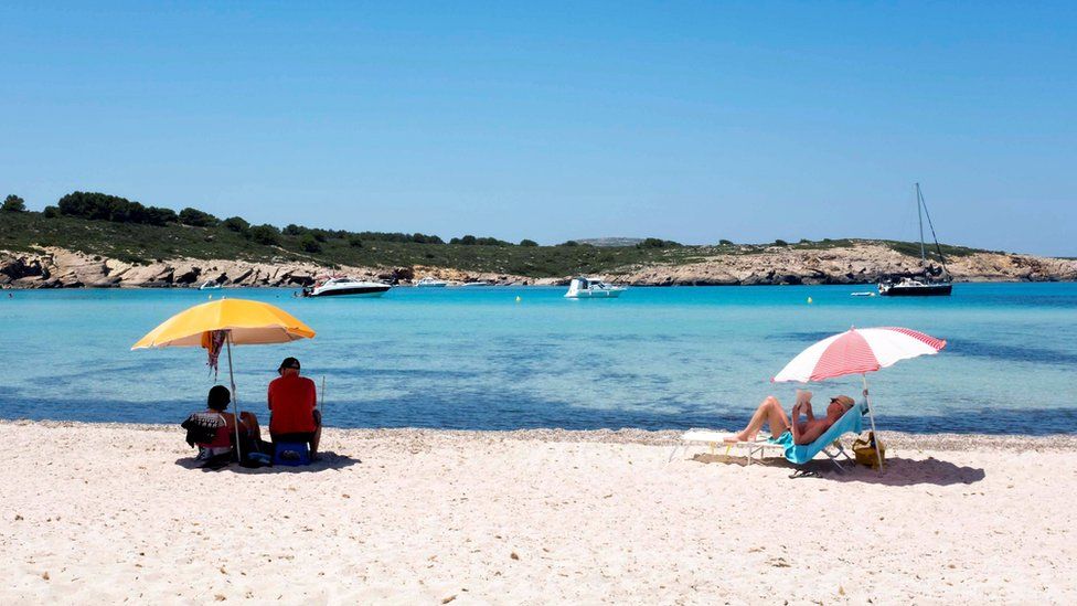 People enjoy warm weather at a beach in Menorca