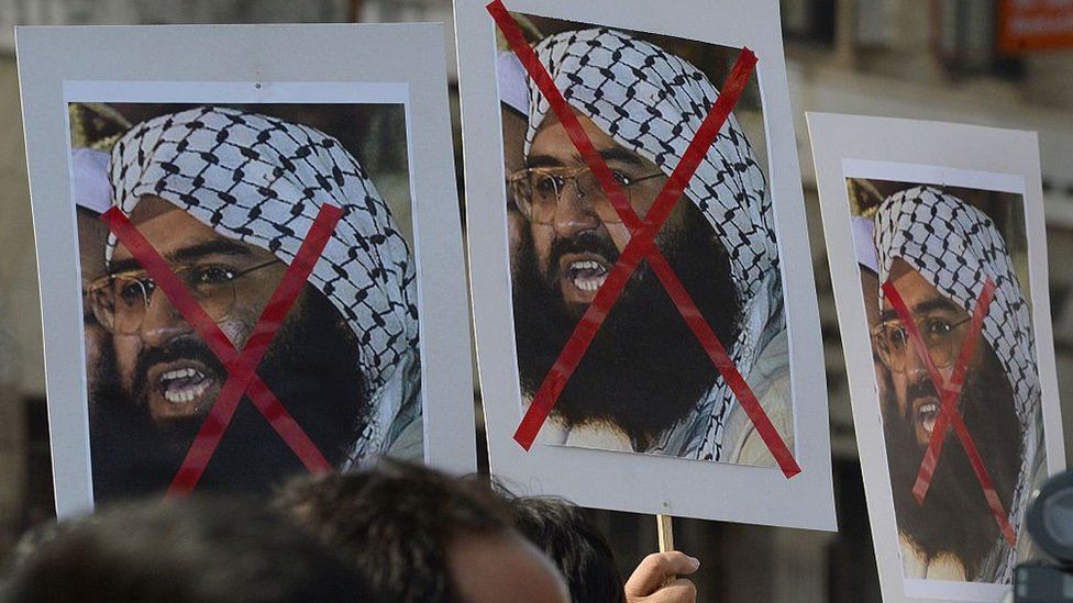 People protest carrying placards of Maulana Masood Azhar