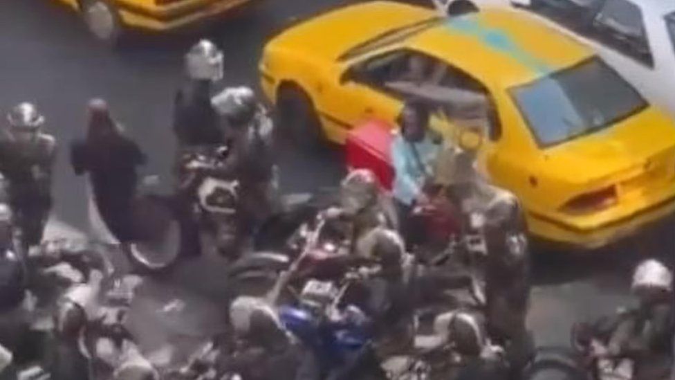 Still from video showing woman fleeing from police in Iran