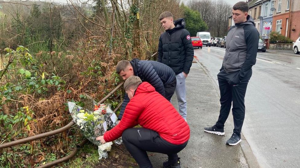 Boys leaving flowers at the scene of the crash