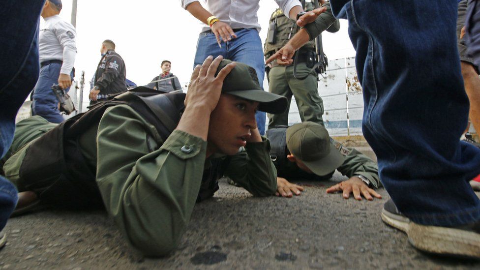 wo Venezuelan soldiers lie on the ground as they are detained by Colombian police