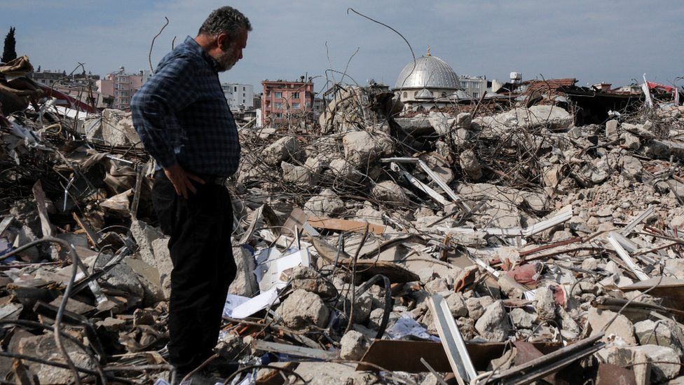 A man looks at a flattened building in Hatay, south-eastern Turkey. Photo: 25 February 2023