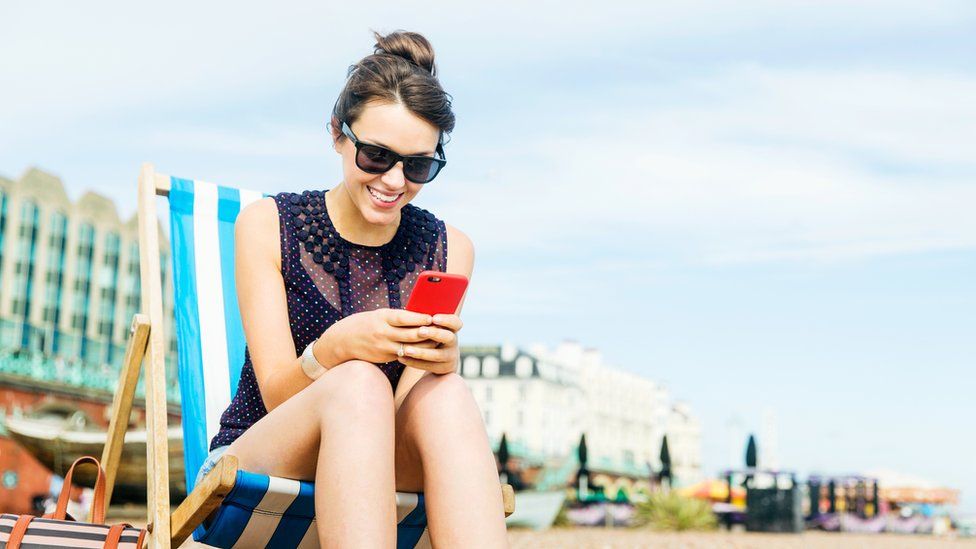 Woman sitting in a deckchair looking at her phone