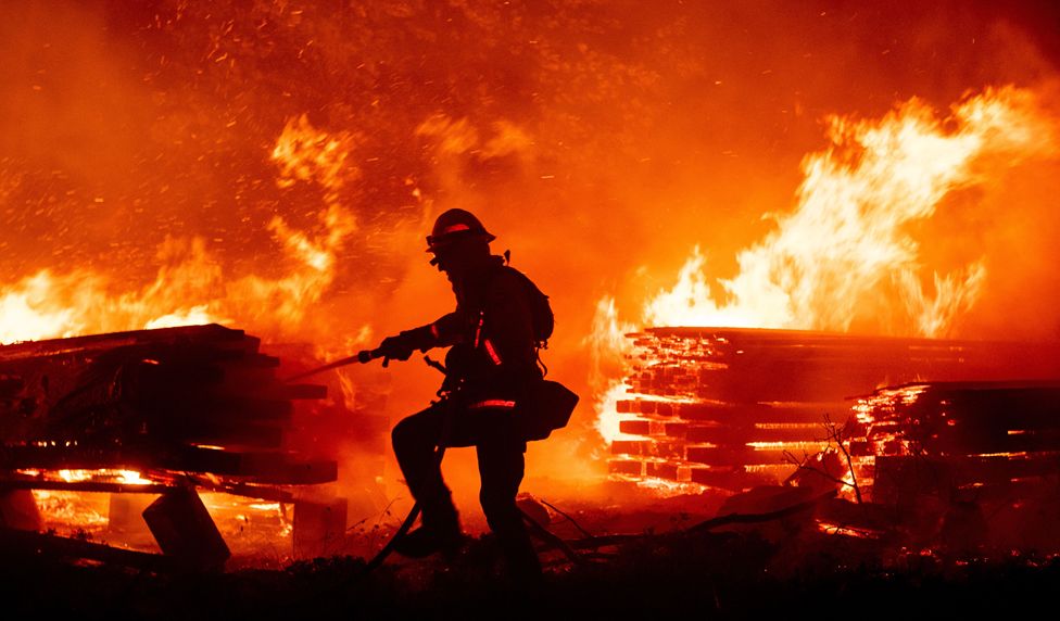 Пожарный тушит пламя, когда они продвигаются к домам во время пожара в ручье в районе Каскадель-Вудс некорпоративного округа Мадера, Калифорния, 7 сентября 2020 года