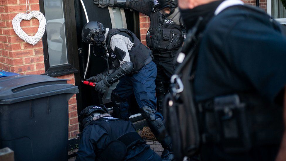 Officers break down a door