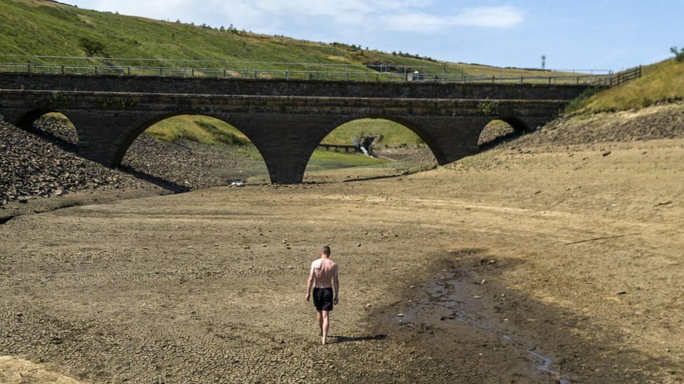 A man walks on the dry ground at Dowry reservoir, near to Oldham