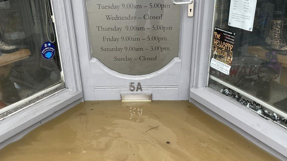 Flood water reaches the letterbox in the middle of the shop door. 